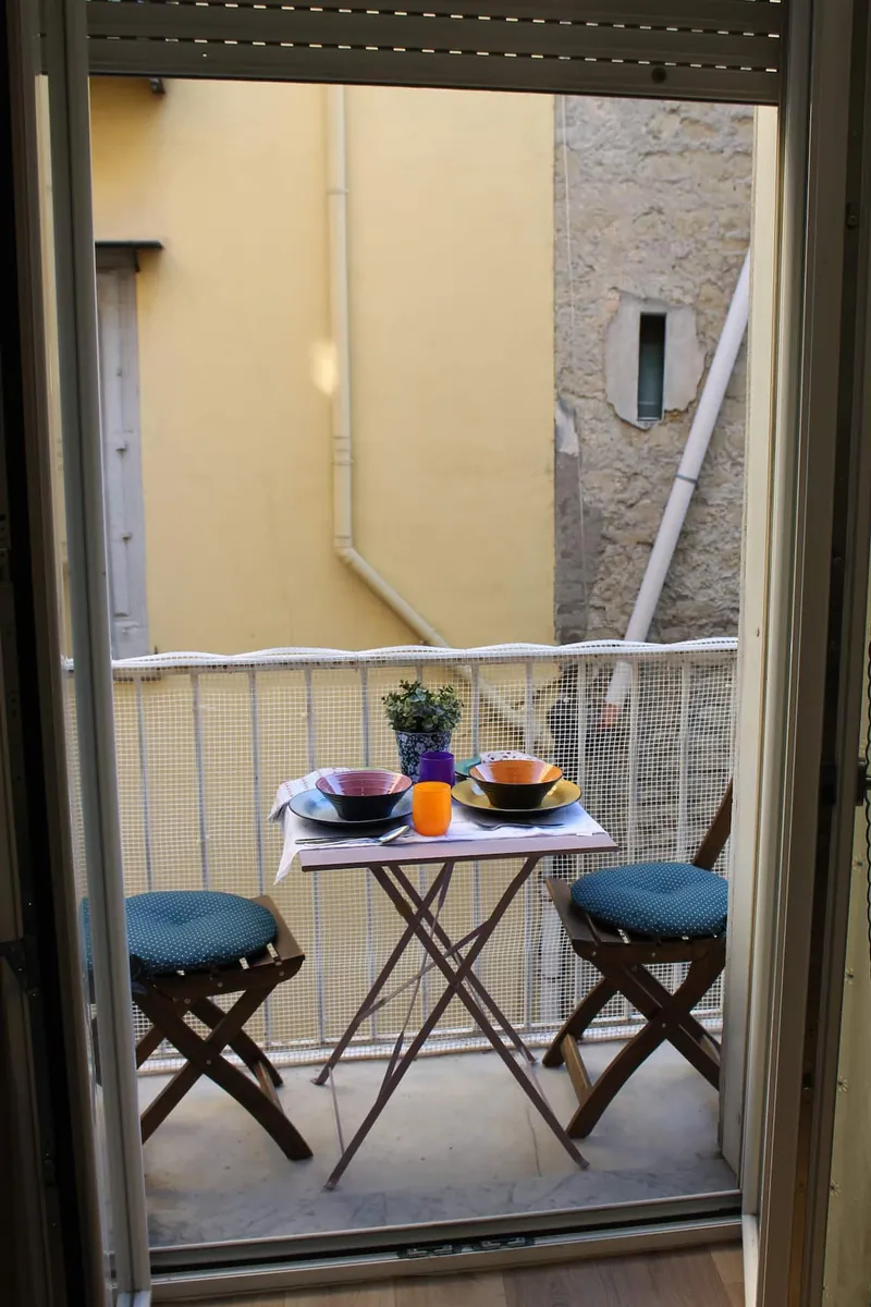 Il tavolino apparecchiato sul balcone, visto dalla porta-finestra.