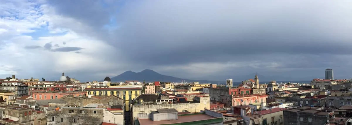 I tetti di Napoli e il Vesuvio sotto un cielo di nuvole.